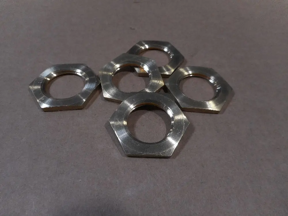 Fünf metallische Sechskantmuttern liegen auf einer grauen Oberfläche. Sie sind für den Einsatz in Verbindung mit Remeha-Produkten geeignet.